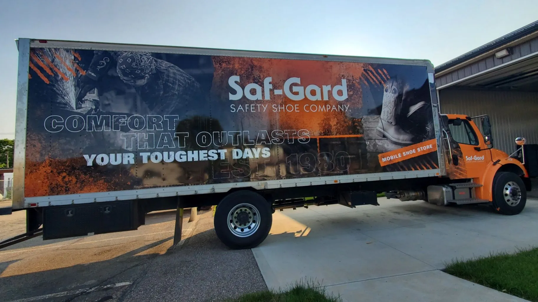 Orange box truck featuring a custom vehicle wrap for Saf-Gard